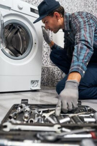 Мастер по ремонту стиральных машин тянется за инструментом