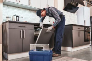 Мастер ремонтирует посудомоечную машину
