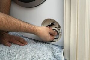 Мастер сливает воду со стиральной машины
