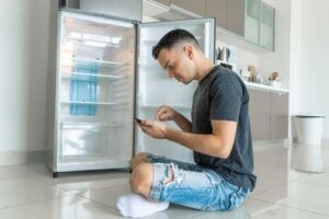 Парень вызывает мастера для ремонта холодильника