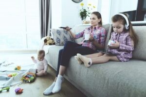 Женщина с детьми смотрит телевизор на диване